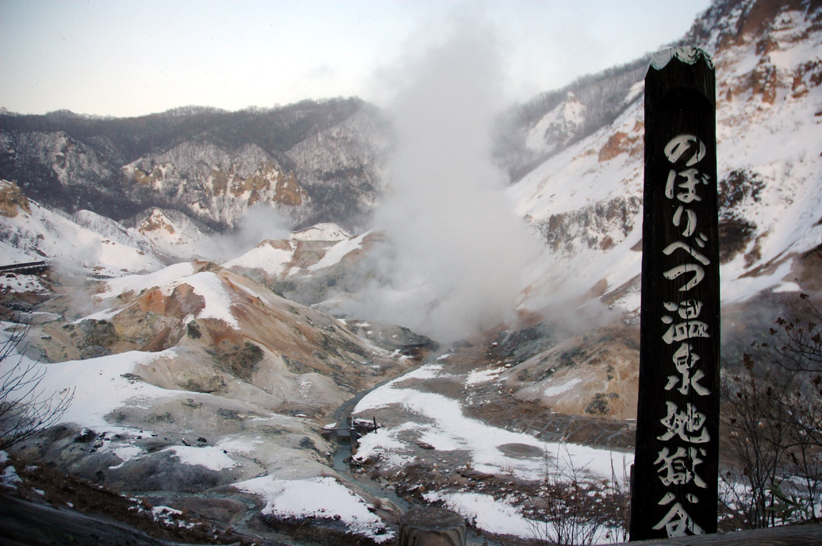 Four wooden totem heads with decorative carvings, displaying a somber expression with downward slanted eyebrows and profil...